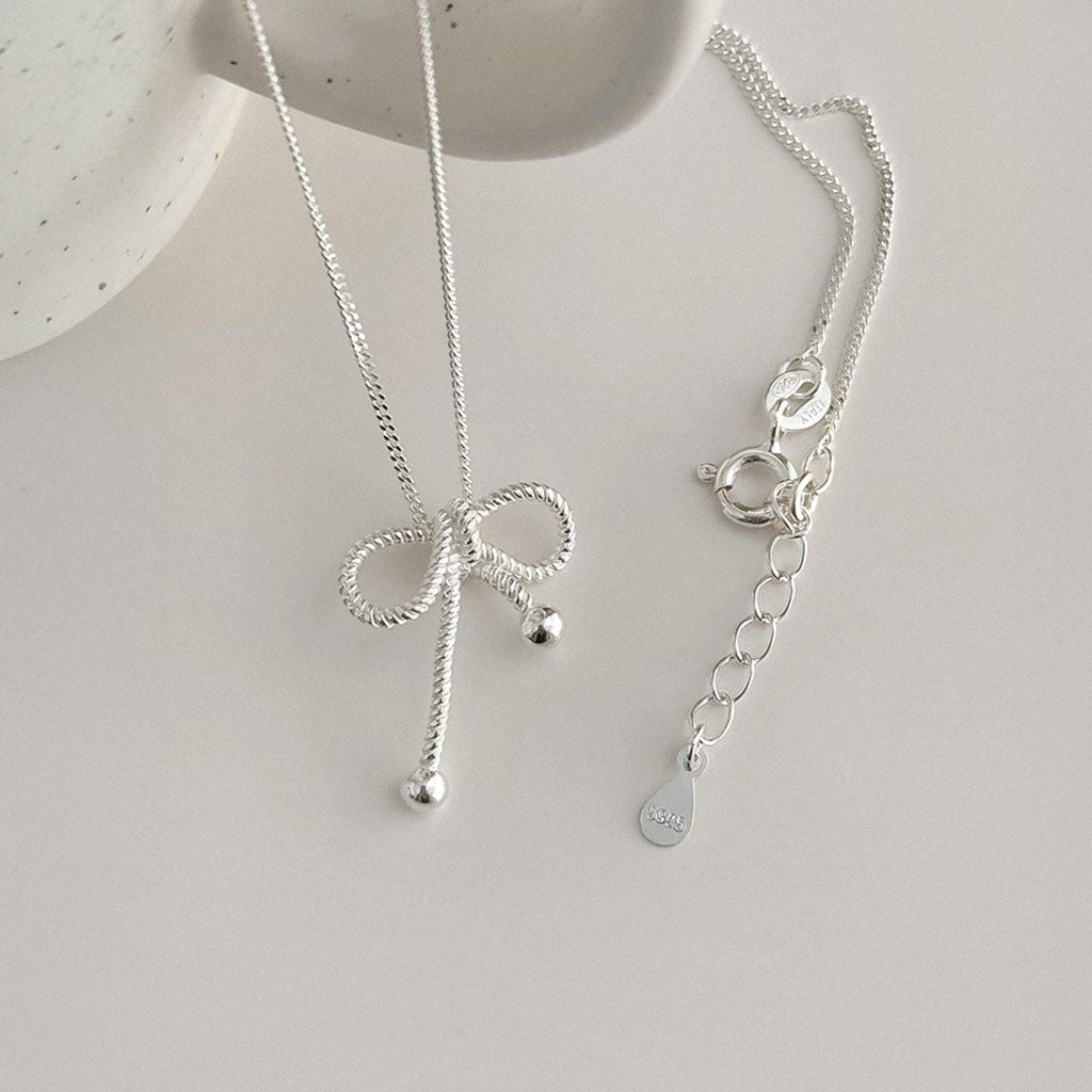 Sterling silver rope bow pendant necklace with delicate ribbon detail on a white background